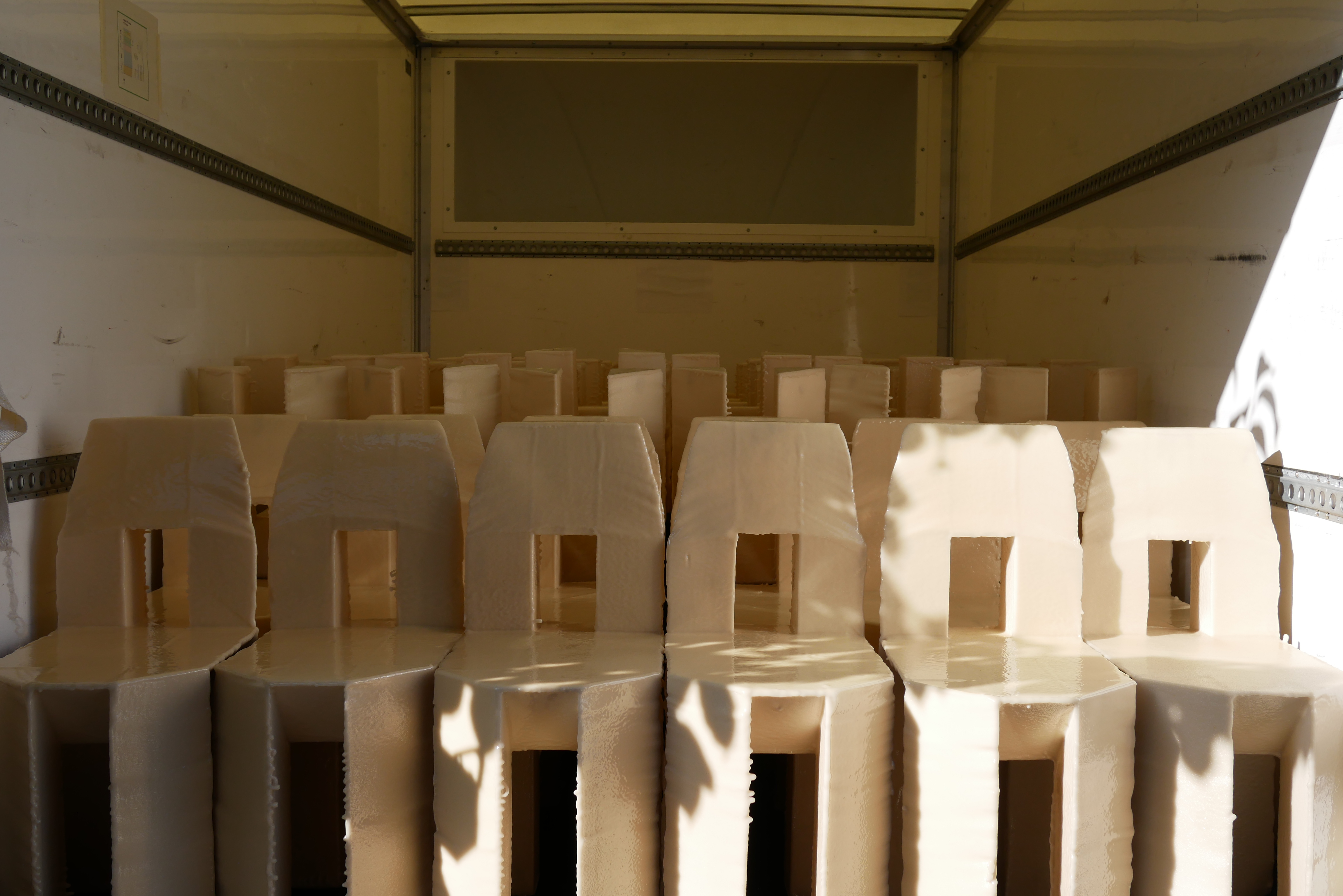 A group of cream chairs with a square cut out in the back sit inside a room.