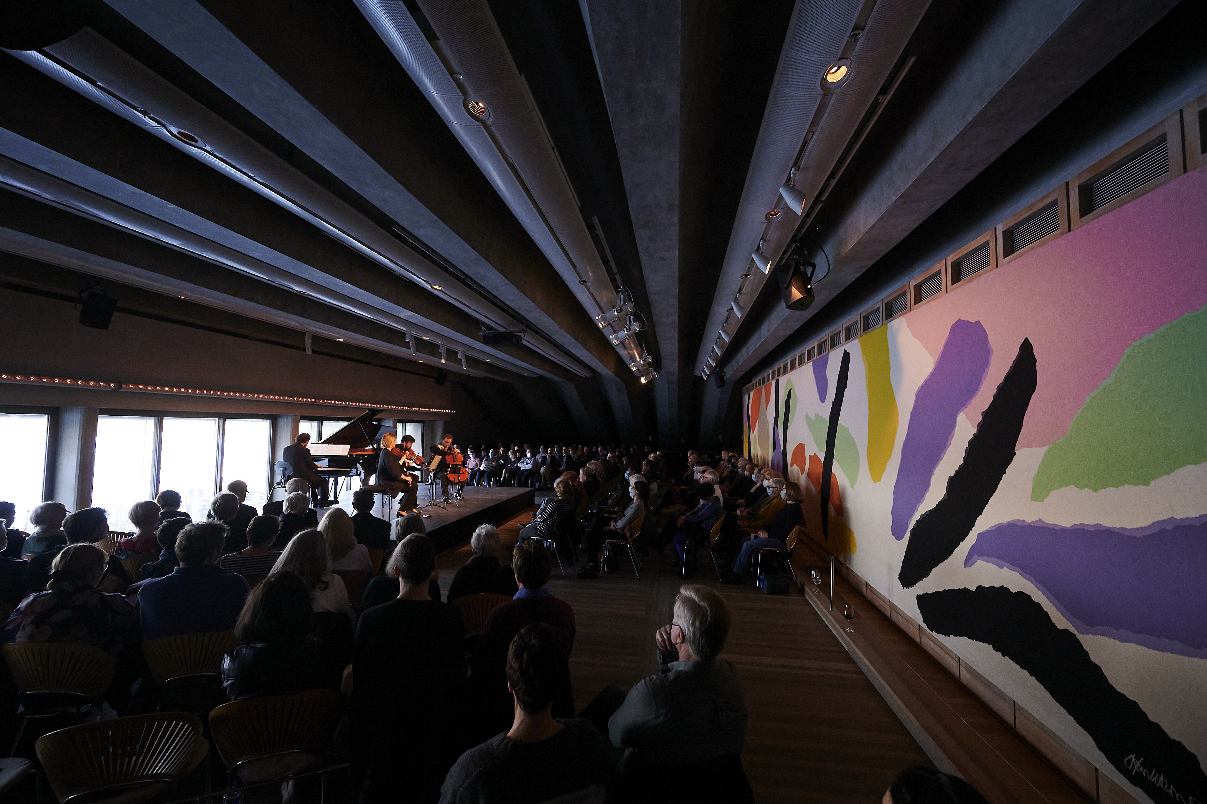 A group of people in Utzon room listening to a pianist.