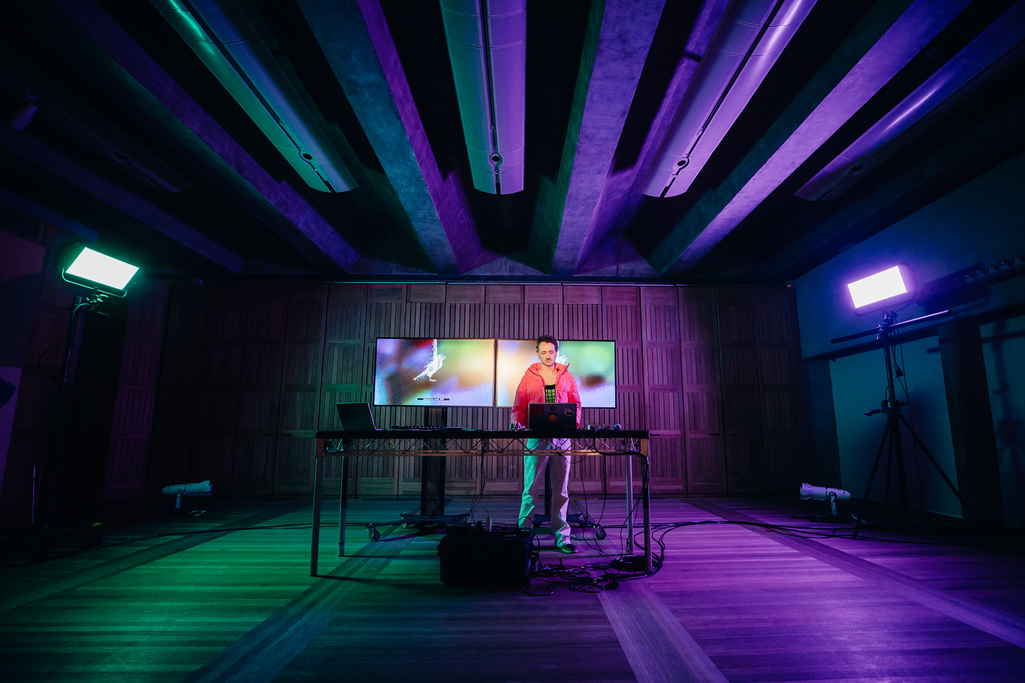 A person standing in a dark room with two screens in the background