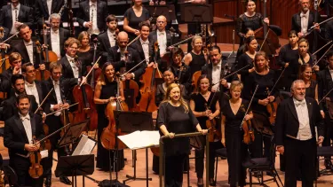 Conductor Simone Young stands with the Sydney Symphony Orchestra as they receive applause