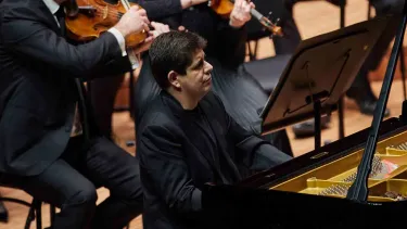 Javier Perianes in an all black suit plays the piano.