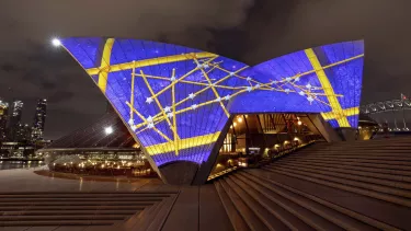 An image of stars and wayfinding projected onto the side of the Opera House sails