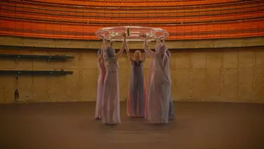 A group of women holding a swim ring above their heads in a circle.