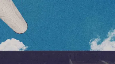 Two chimney stacks reach a blue sky.