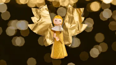 A golden doll of a Christmas Caroler with paper angel wings