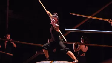 A woman holding a long pole, performing on stage.