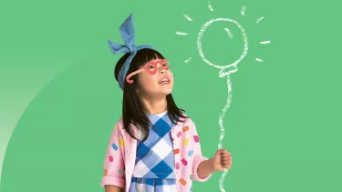 An Asian girl holding a pretend balloon which is glowing.