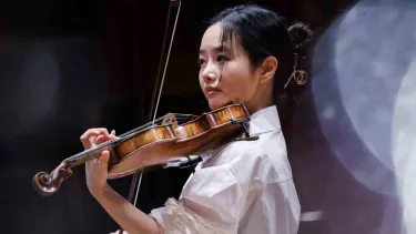 Bomsori Kim plays the violin in a white shirt.