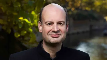 Stephen Layton stands in front of a river.