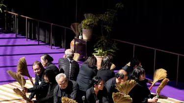 A group of people sitting in a circle with broom sticks in their hands.