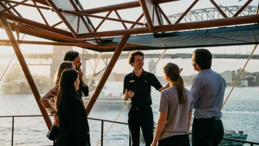 A tour guide with a group of people outside the Sydney opera house.