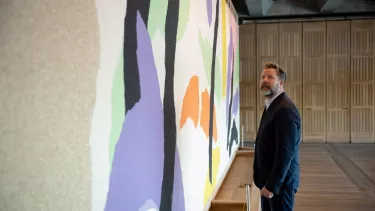 A man in a suit staring at artwork on a wall.