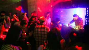 A DJ performing on stage to a lively audience.