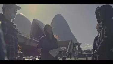 Megan Cope holding a piece of paper in front of the Opera House.