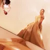 Woman in gold ballgown stands away from other partygoers