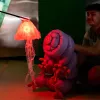 A puppet looks up at a lit jelly fish.