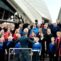 A group of people singing on the steps of the Sydney Opera House.