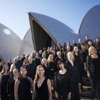 A group of people wearing black on the steps of the Sydney Opera House on a sunny day.