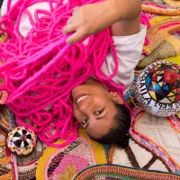 A woman is lying on the floor surrounded by pink yarn.