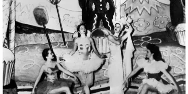 A group of ballet dancers in front of a Christmas backdrop.