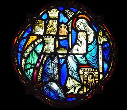A medieval glass stained window of three kings bringing gifts to the Mother Mary and Jesus