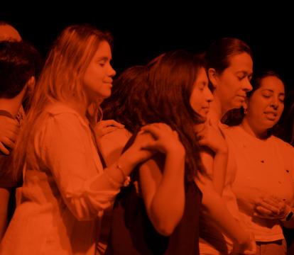 Image of a small group of people in orange light in a dance performance.
