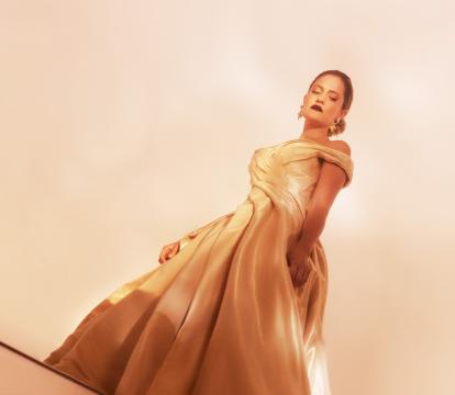 Woman in gold ballgown stands away from other partygoers