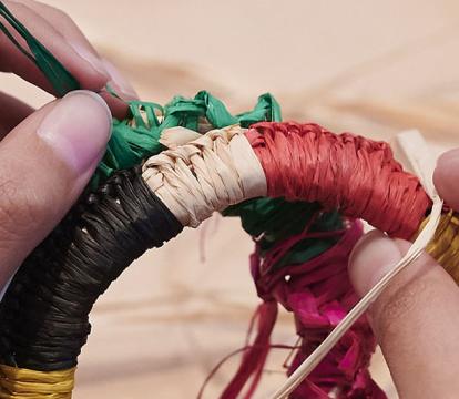 A close up of hands weaving using a traditional Aboriginal technique