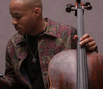 Sheku Kanneh-Mason with a floral jacket holding his Cello.