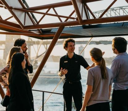 A tour guide with a group of people outside the Sydney opera house.