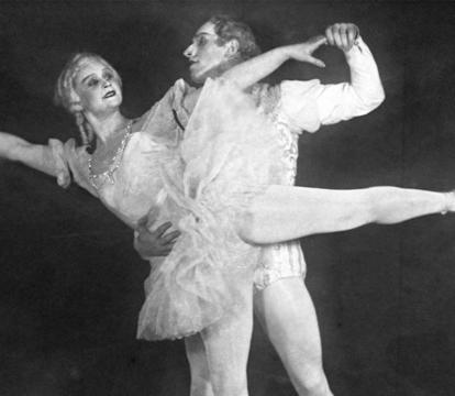 A man and woman in white outfits, dancing,