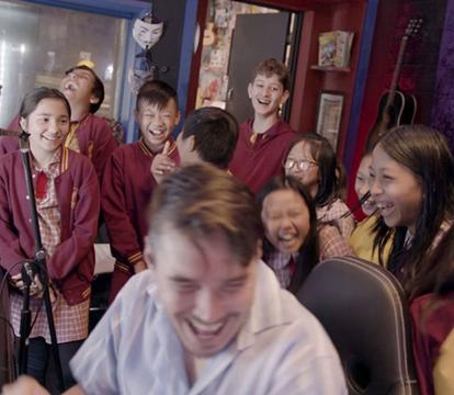 A man surrounded by school kids in a recording studio.