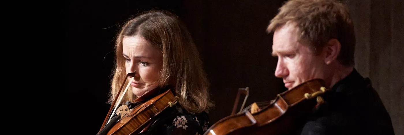 A closeup of two violin players side by side