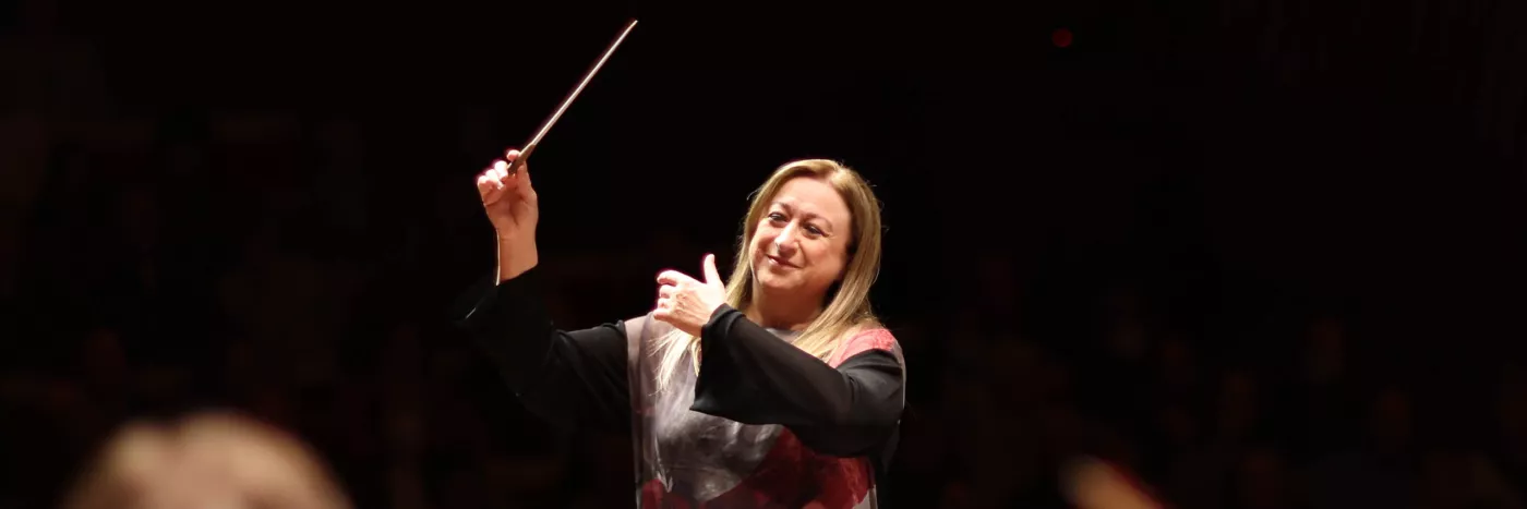 Simone Young conducts with baton in the hand in front of an orchestra