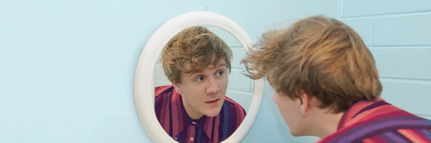 Josh Thomas staring into a mirror