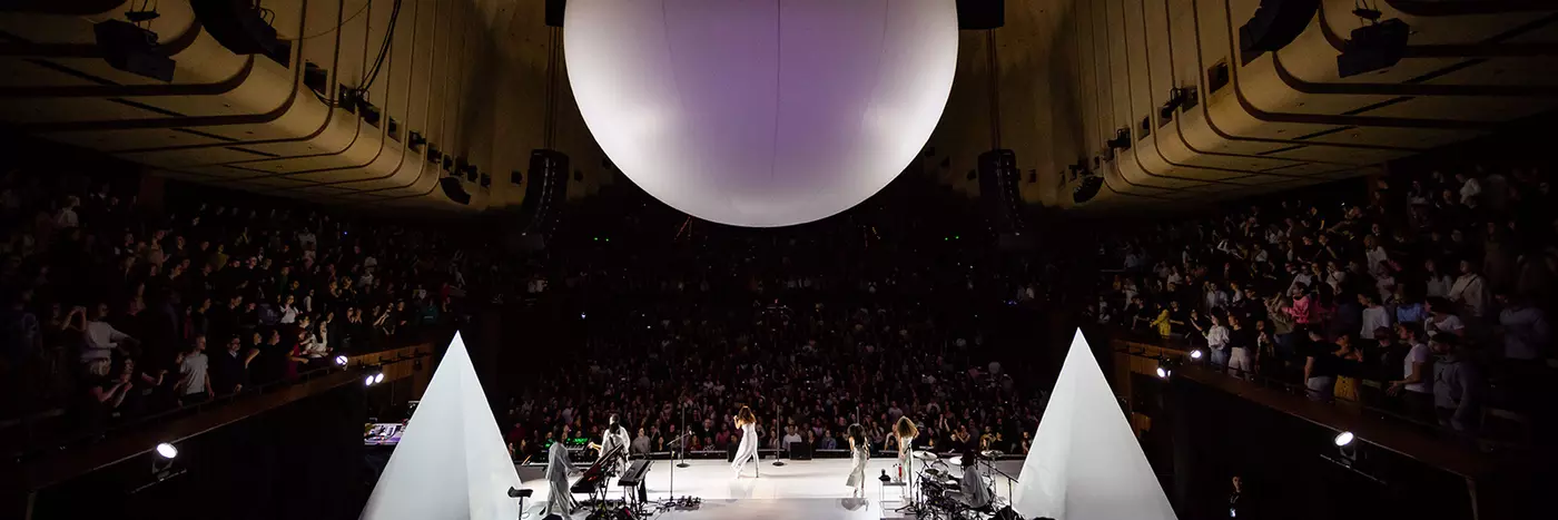 A group of musicians performing on the stage with a big balloon above them.