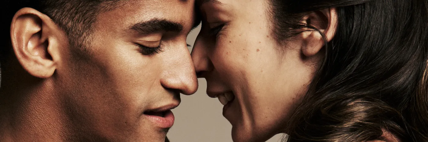 Two dancers with their faces close to touching, eyes closed.