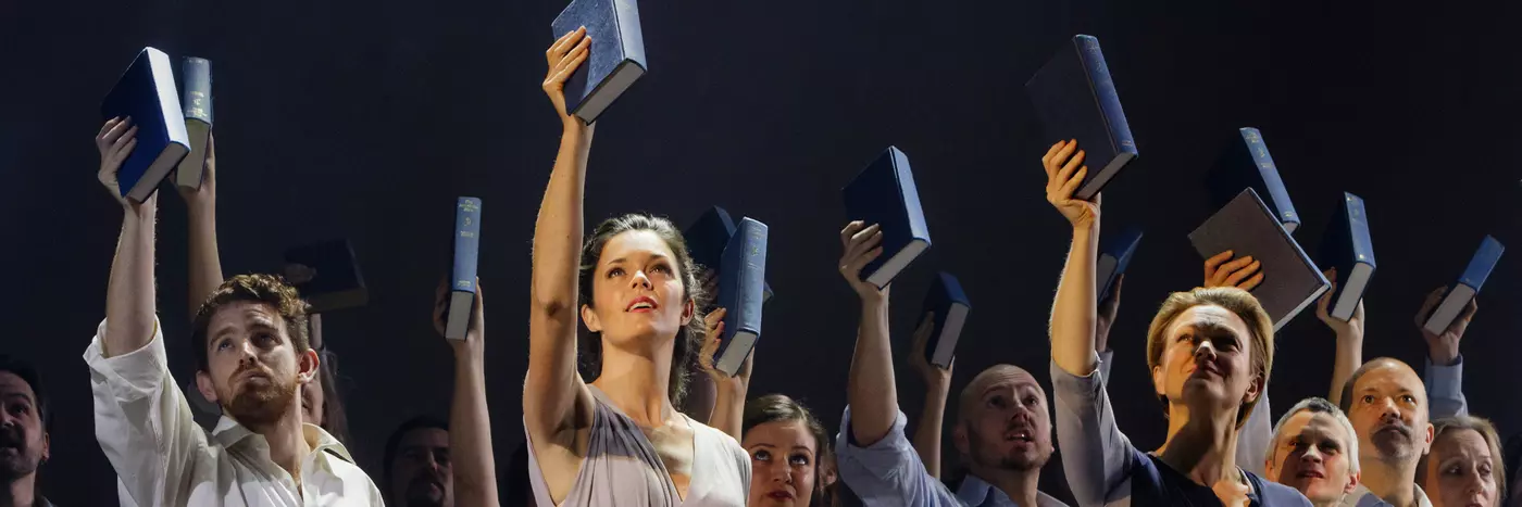 The cast wears neutral outfits, all holding up a book in their right hand