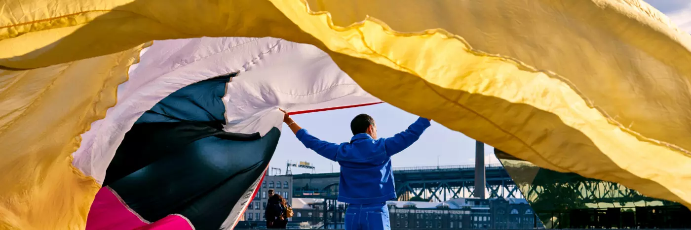 A man holding a long colourful curtain.