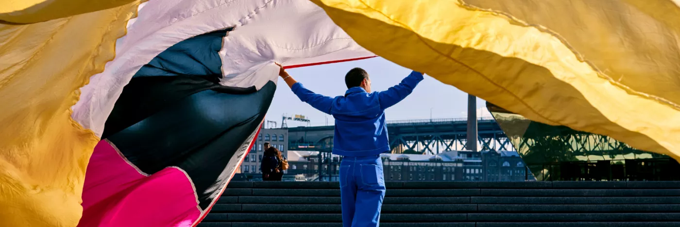 A man holding a long colourful curtain.