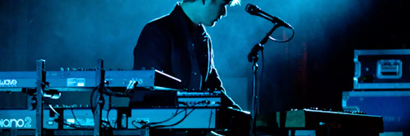 A man performing on a blue-lit stage.