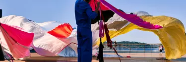 A man holding a long colourful curtain.